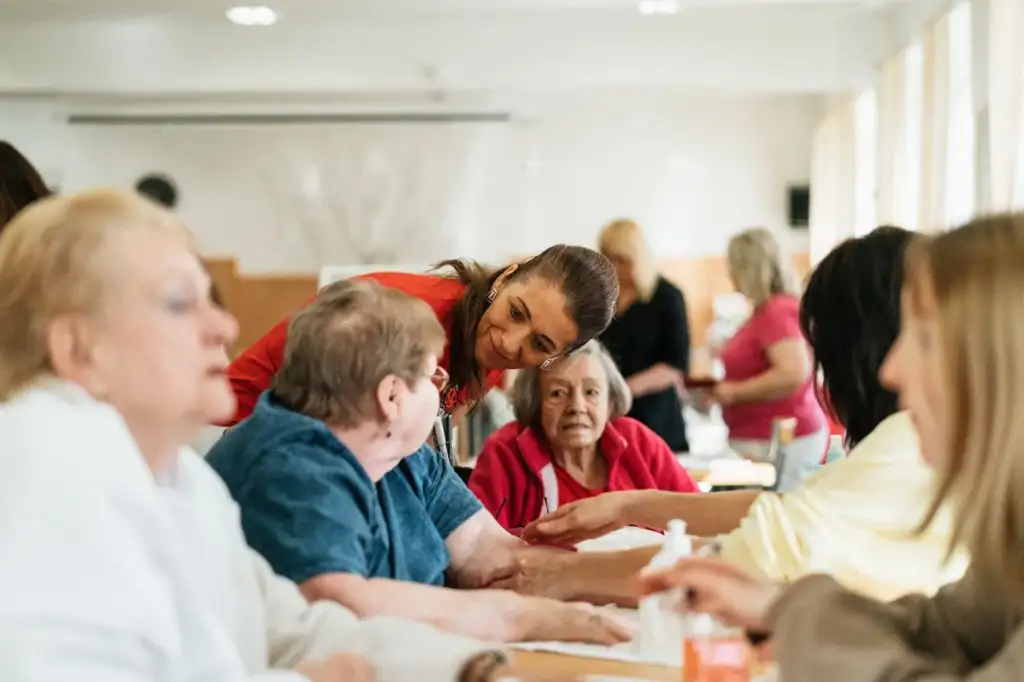 A caregiver talking with a group of older adults at a table