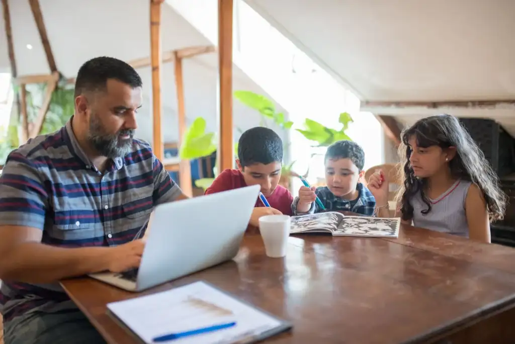 A father and his children working through paperwork at the table