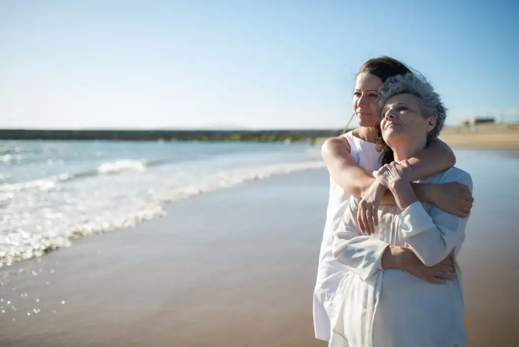 An adult daughter hugging her older mother outdoors